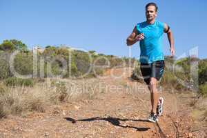 Athletic man jogging on country trail