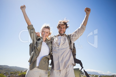 Hiking couple standing on mountain terrain smiling at camera