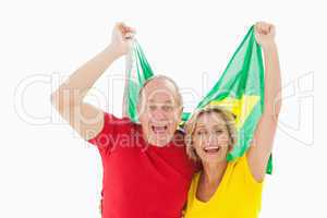 Happy older couple cheering at camera holding brazil flag