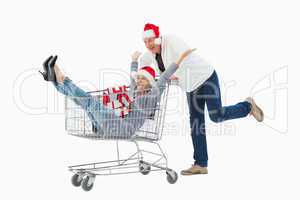 Festive mature couple in winter clothes with trolley and gifts