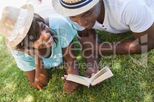 Happy young couple reading book on the grass