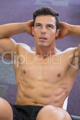 Muscular man doing abdominal crunches in gym