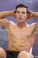 Muscular man doing abdominal crunches in gym