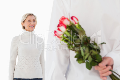 Man hiding bouquet of roses from older woman