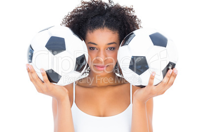 Pretty girl holding footballs and looking at camera