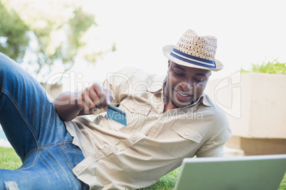 Handsome man relaxing in his garden using laptop to shop
