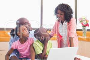 Cute siblings using laptop together with parents