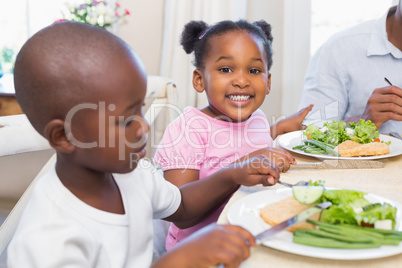 Family enjoying a healthy meal together with daughter smiling at