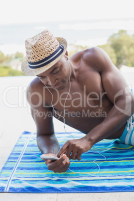 Handsome shirtless man listening to music poolside