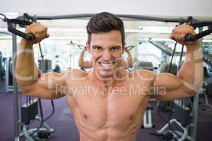 Shirtless muscular man using resistance band in gym