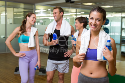 Fit woman smiling at camera in busy fitness studio