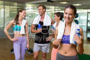 Fit woman smiling at camera in busy fitness studio