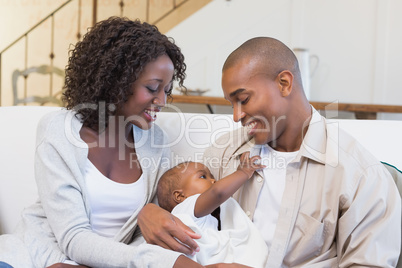 Happy young parents spending time with baby on the couch