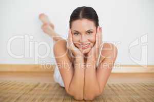 Smiling brunette lying on floor looking at camera
