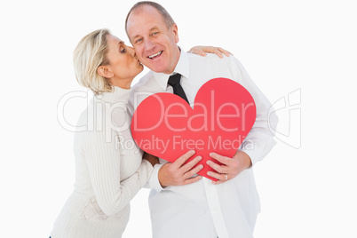 Older affectionate couple holding red heart shape