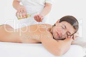 Attractive woman getting massage oil on her back