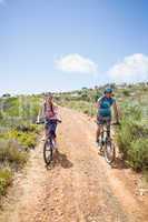 Fit couple cycling up mountain trail