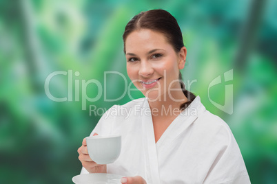 Beautiful brunette in bathrobe drinking herbal tea