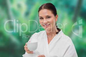 Beautiful brunette in bathrobe drinking herbal tea