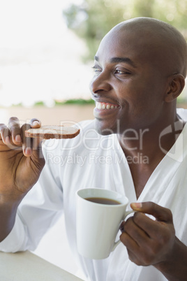 Handsome man in bathrobe having breakfast outside