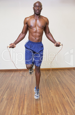 Shirtless muscular man skipping in gym