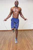 Shirtless muscular man skipping in gym