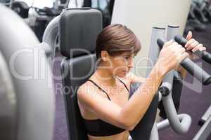 Happy brunette using weights machine for arms