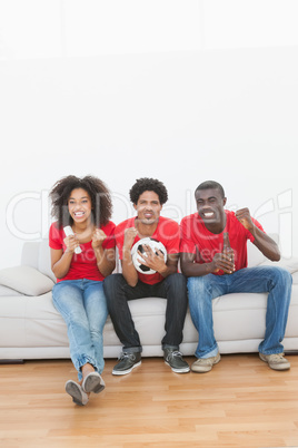 Football fans sitting on couch cheering together