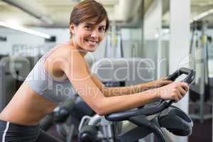 Fit brunette working out on the exercise bike