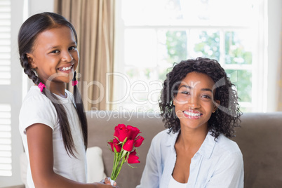 Pretty mother sitting on the couch with her daughter offering ro