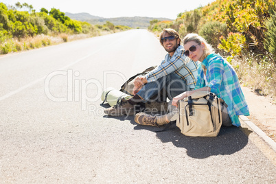 Attractive couple sitting on the road waiting for a lift