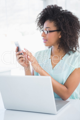 Happy hipster businesswoman working on laptop sending a text