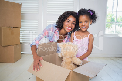 Cute daughter unpacking her teddy bear with mother