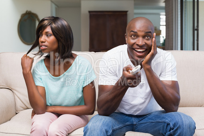 Bored woman sitting next to her boyfriend watching tv