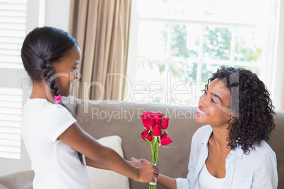 Pretty mother sitting on the couch with her daughter offering ro