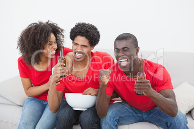 Football fans sitting on couch cheering together