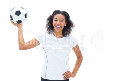 Pretty football fan in white smiling at camera holding ball