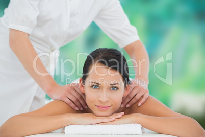 Beautiful brunette enjoying a shoulder massage smiling at camera
