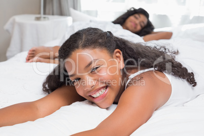 Happy mother and daughter relaxing on bed together