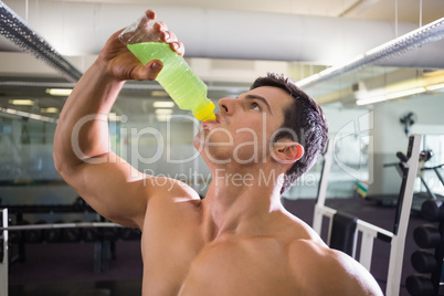 Sporty young man drinking energy drink in gym