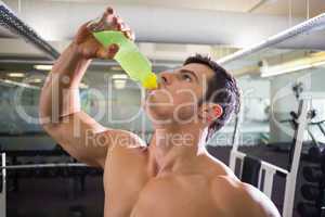 Sporty young man drinking energy drink in gym