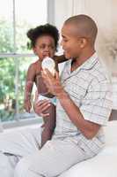 Happy father trying to feed his cranky baby girl