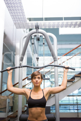 Fit brunette using weights machine for arms