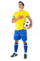 Football player in yellow with ball listening to anthem