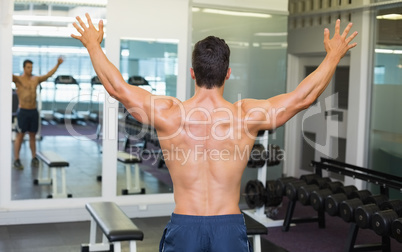 Bodybuilder with arms outstretched in gym