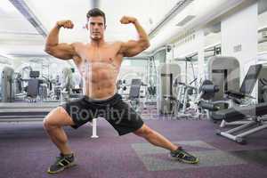 Shirtless muscular man flexing muscles in gym