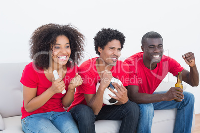 Football fans in red sitting on couch cheering