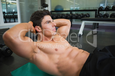 Muscular man doing abdominal crunches in gym