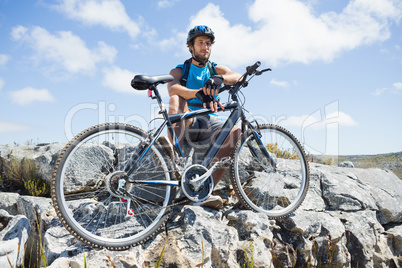 Fit cyclist taking a break on rocky peak