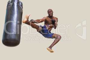 Shirtless muscular boxer kicking punching bag